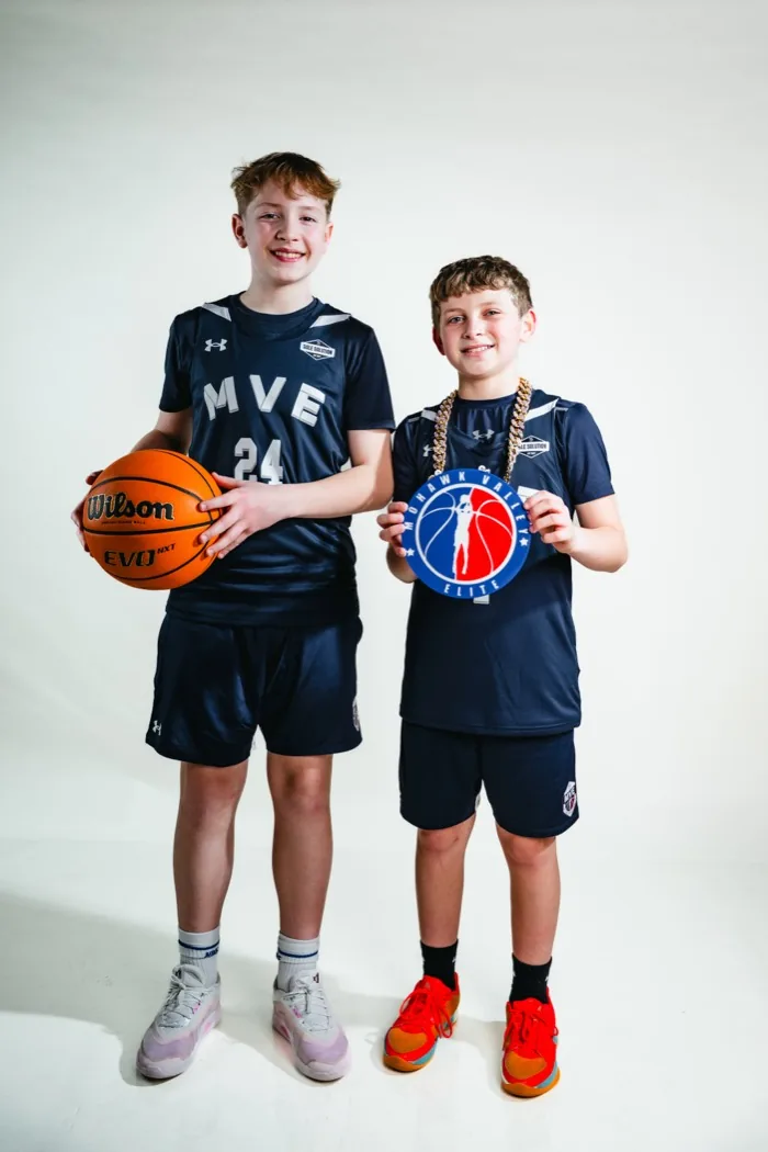Two MVE teammates at 2026 Media Day, one holding a basketball and one wearing the player-of-the-game chain